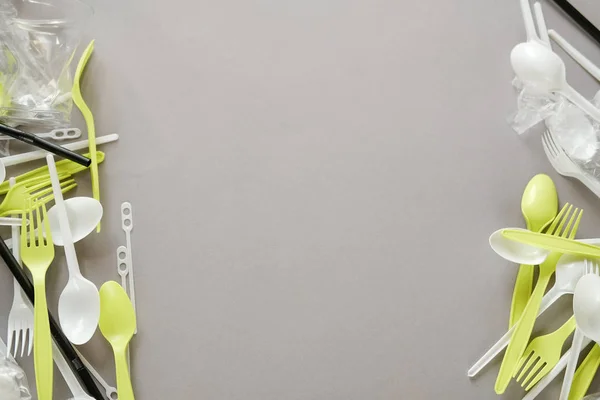 Plastik beyaz kaşıklar ve yeşil çatallar. gri arka plan. Ekoloji kavramı. kağıt alternatif olarak