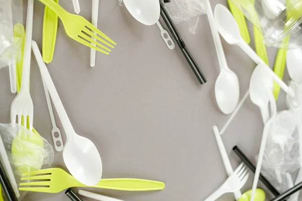 Plastik beyaz kaşıklar ve yeşil çatallar. gri arka plan. Ekoloji kavramı. kağıt alternatif olarak