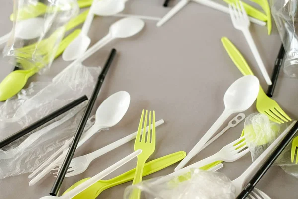 Plastik beyaz kaşıklar ve yeşil çatallar. gri arka plan. Ekoloji kavramı. kağıt alternatif olarak