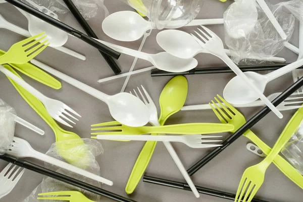 Plastik beyaz kaşıklar ve yeşil çatallar. gri arka plan. Ekoloji kavramı. kağıt alternatif olarak