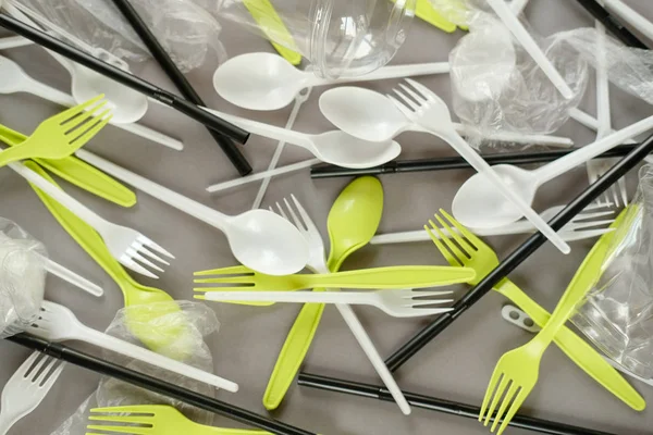 Plastik beyaz kaşıklar ve yeşil çatallar. gri arka plan. Ekoloji kavramı. kağıt alternatif olarak
