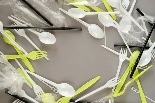 Plastik beyaz kaşıklar ve yeşil çatallar. gri arka plan. Ekoloji kavramı. kağıt alternatif olarak