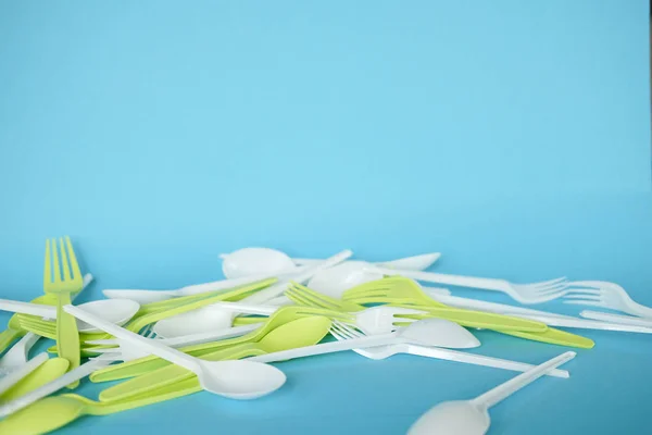 Plastik beyaz kaşıklar ve yeşil çatallar. mavi arka plan. ekoloji. 