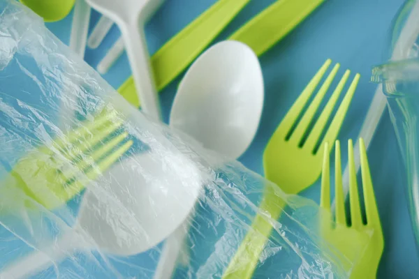 Plastik beyaz kaşıklar ve yeşil çatallar. mavi arka plan. ekoloji. 
