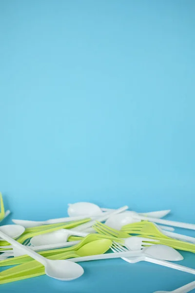 Plastik beyaz kaşıklar ve yeşil çatallar. mavi arka plan. ekoloji. 