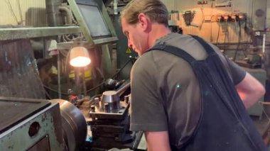 Bir tornalama ve frezeleme makinesinin arkasında turner. Çizime göre ürün tornalama. Taşlama silindiri. Sanayi fabrikası.