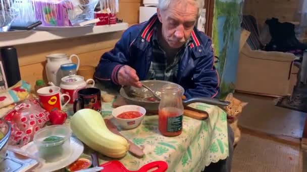 一位老人在一间乡村别墅的厨房里与一只红猫共进晚餐 — 图库视频影像
