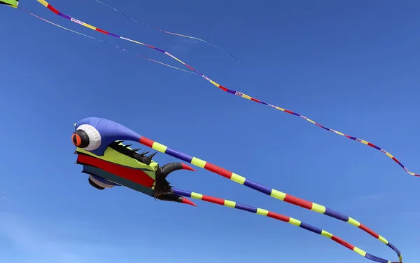 Beautiful striped kite against the blue sky — Stock Photo, Image