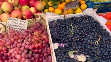 Marketteki tezgahta, ahşap ve plastik kasalarda çeşitli lezzetli doğal meyveler var. Üzüm, limon, elma, armut, mandalina, hurma.