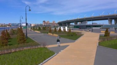 PETERSBURG, RUSSIA - 22 Mayıs 2020: siyah kazaklı ve gri pantolonlu bir adam gezinti güvertesi boyunca koşuyor. Şehrin üzerinde İHA uçuşu.