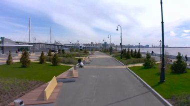 PETERSBURG, RUSSIA - 22 Mayıs 2020: bebek arabalı bir adam gezinti güvertesi boyunca paten sürüyor. Şehrin üzerinde İHA uçuşu.