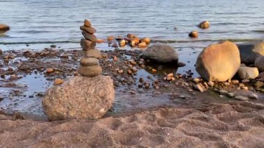 Nehir suyunun arka planında taş piramit. Basit dengeli çakıl taşları, zen taşı heykel, nehir taşlarından bir kule. Uyum, denge ve sadelik kavramı.