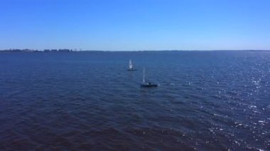 Denizde üç beyaz yat. Yatçılar güzel mavi denizde yelken açarlar..