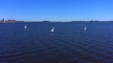 Denizde üç beyaz yat. Yatçılar güzel mavi denizde yelken açarlar..