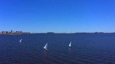 Denizde üç beyaz yat. Yatçılar güzel mavi denizde yelken açarlar..