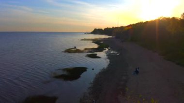 St. PETERSBURG, Rusya - 24 Mayıs 2020: günbatımında güzel sahil ve mavi deniz. Kumsalda dinlenen insanların hava videosu..
