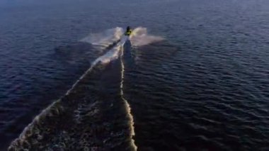 PETERSBURG, RUSSIA - 24 Mayıs 2020: bir jiroskopi güzel mavi denizi gün batımında keser. Bir jet ski üzerinde dinlenen insanların hava videosu..
