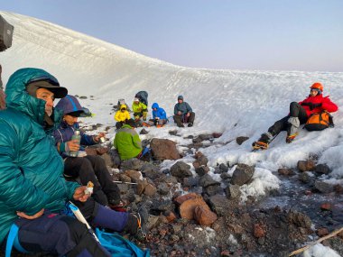 ELBRUS DISTRICT, RUSSIA - 7 Temmuz 2020: Sırt çantaları ve yürüyüş direkleriyle dağcılar durdular. Güzel dağ kış manzarası. Kuzey Elbrus bölgesinin karlı yamaçları.