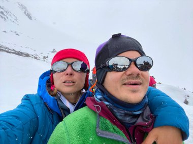 İki dağcı, bir erkek ve bir kız kuzey Elbrus bölgesinin karlı yamacında selfie çekiyorlar. Güzel dağ kış manzarası.