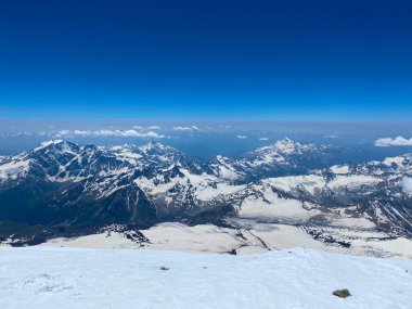 Elbrus 'un tepesinden nefes kesici bir manzara. Güzel kış dağ manzarası. Kuzey Elbrus bölgesinin kayalık yamaçları. Mavi gökyüzü