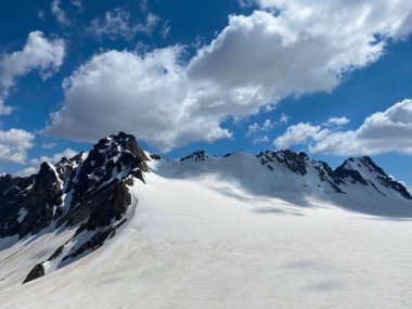 Güzel bir kış dağ manzarasının havadan görünüşü. Kuzey Elbrus bölgesinin kayalık yamaçları. Beyaz bulutlu mavi gökyüzü.