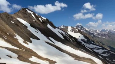 Elbrus Dağı. Güzel bir dağ kış manzarasının havadan görünüşü. Kuzey Elbrus bölgesinin kayalık yamaçları. Mavi gökyüzü ve beyaz bulutlar. Dairesel Panorama.