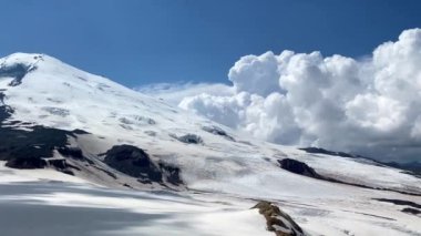 Elbrus Dağı. Güzel bir dağ kış manzarasının havadan görünüşü. Kuzey Elbrus bölgesinin kayalık yamaçları. Mavi gökyüzü ve beyaz bulutlar. Dairesel Panorama.