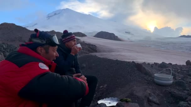 登山者 旅行者们坐在Elbrus脚下喝茶 喝着巧克力 美丽的山地冬季风景的空中景观 — 图库视频影像