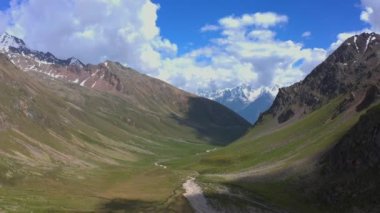 Güzel bir dağ kış manzarasının havadan görünüşü. Kuzey Elbrus bölgesinin kayalık yamaçları. Beyaz bulutlu mavi gökyüzü.