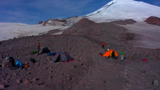 帐篷营地在Elbrus山前面旅行者收集他们的背包 Elbrus北部地区的雪质岩石斜坡 山区冬季景观 — 图库视频影像