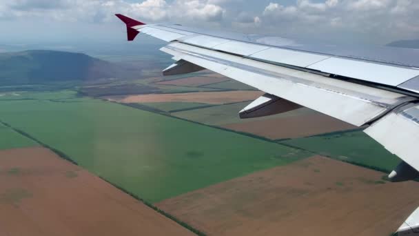 Kilátás a repülőgép szárnyára az utastérből. Kilátás a repülőgép ablakából lefelé a föld felszínére.