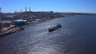 Nehir kıyısında bir sıra inşaatın ya da kargo vincinin havadan görüntüsü ve yakınlarda bir gemi var. Gemi Kanonersky Adası 'na yanaşıyor. Su mavnaları ve nakliye araçlarıyla sanayi limanı.