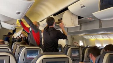 PETROPAVLOVSK-KAMCHATSKY, RUSSIA - 15 Eylül 2020: Koruyucu maskeli uçak yolcuları bagajlarını üst ranzaya koyup koltuklarına oturdular.