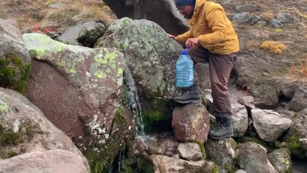 Turista Brýlích Žluté Bundě Sbírá Čistou Horskou Vodu Velké Plastové — Stock video