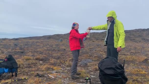 男游客用一小口水来招待他的伴侣 爸爸和女儿在山上 这个女孩用水解渴 在Klyuchevskoy火山公园旅行 前往堪察加半岛 — 图库视频影像