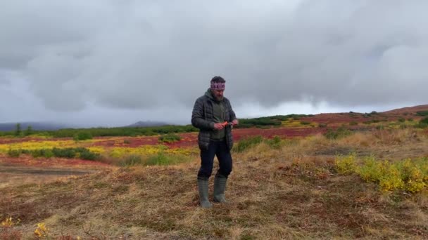 男は野原で信号の火を灯す クリウチェフスキー火山公園でのトレッキング カムチャツカ半島への旅行 — ストック動画