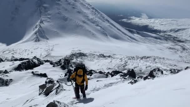 一个冒险家 一个拿着冰斧的登山者沿着白雪覆盖的小径爬到火山顶上 爬山在Klyuchevskoy火山公园旅行 前往堪察加半岛 — 图库视频影像