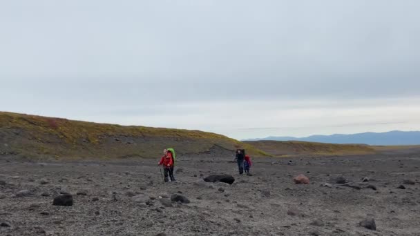 三个背著背包和远足杆子的游客正沿着烧焦的土地和熔岩平原散步 在Klyuchevskoy火山公园旅行 前往堪察加半岛 — 图库视频影像