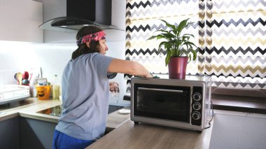 Bir kadın mikrodalga fırın yıkar. Bir öğrenci mutfaktaki mikrodalganın tozunu alıyor. Daireyi temizliyorum. Hizmetçi daireyi temizliyor. Bandana takıyor.