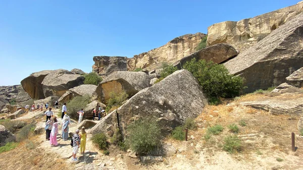 GOBUSTAN, AZERBAIJAN - 17 Temmuz 2025: Bir grup turist büyük bir kaya oluşumunun yakınında yürüyorlar. Gobustan Eyaleti Tarihi ve Sanatsal Rezervi. Gezmek ve turizm