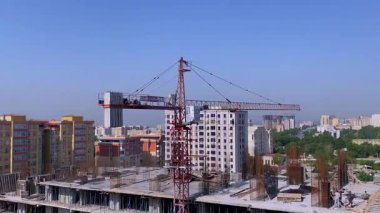 DUSHANBE, TAJIKISTAN 12 Mayıs 2025: Şehrin yüksek bir inşaat alanında bir vinç görüntüsü. Bir grup inşaat işçisi üst katta çalışıyor.