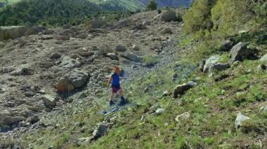 Kovboy şapkalı bir adam Tacikistan 'daki Alaudin Gölleri' ne giderken kayalık bir yamaca tırmanıyor. Turizm ve özgürlük. Maceralar ve yolculuklar