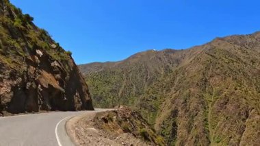 Virajlı yolu olan bir dağ sırası. Yol dar ve dolambaçlı, dağlar ağaçlarla kaplı. Dik kayalıklar. Tacikistan Maceraları