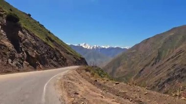 Tehlikeli bir dağ yolunda araba kullanmak. Hayret verici Tacikistan 'dan arabayla geçmek. Birkaç bin metre yükseklikte dolambaçlı bir yolu olan kayalık bir sırt.