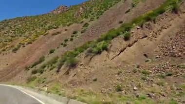 Yolun kenarında kırmızı bir tabela olan bir dağ yolunda tehlikeli dönüşler. Yol dolambaçlı ve manzara nefes kesici. Tacikistan araba gezisi