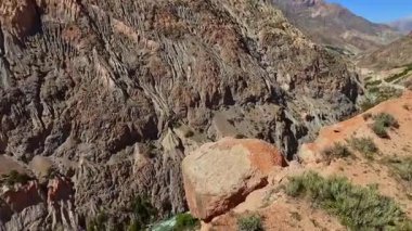 Dağ nehrinin havadan görünüşü ve yeşil eğimli yüksek kaya oluşumları. Tacikistan 'ın doğası. Mountain Lake seyahat turu. Çorak bir arazisi olan bir dağ sırası..