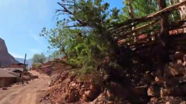 Tacikistan 'ın antik köylerinde araba gezisi. Arka planda dağlar olan kırmızı tuğlalı binalar boyunca toprak kırsal bir yol boyunca sür. Turizm ve macera