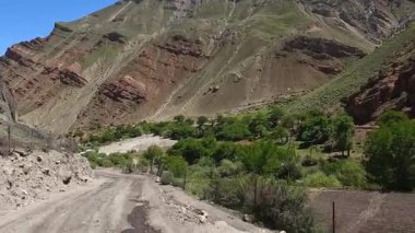 Tacikistan 'da arabayla seyahat ediyor. Engebeli bir toprak yolda güçlü görkemli dağlar, uçurumlar ve tepelere karşı at sürmek. Yol yemyeşil bir vadide esiyor..