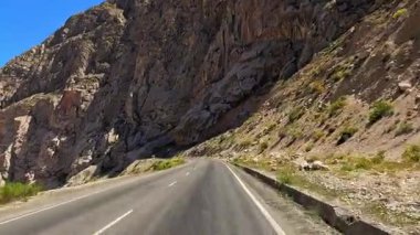 İnanılmaz bir dağ geçidinde yürüyüş. Tacikistan 'a araba gezisi. Yüksek kayalık, mavi gökyüzü ve asfalt yol. Turizm ve macera