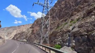 Dağ nehri boyunca dolambaçlı bir yol var. Tacikistan 'daki Varzob vadisinde arabayla seyahat ediyor. Yol boş ve gökyüzü mavi. Turizm ve macera